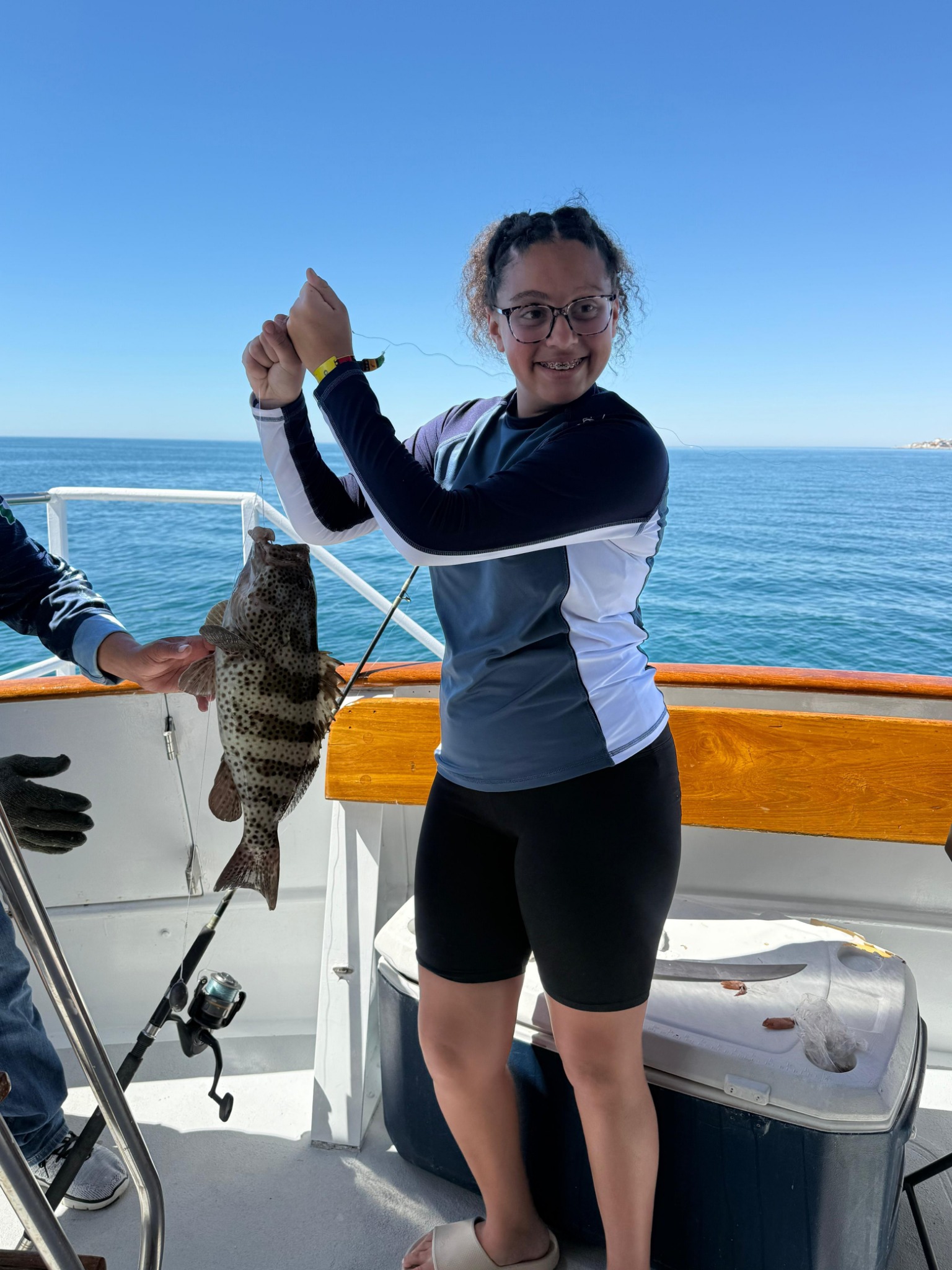 Young guest holding her catch on a Rocky Point family fishing trip